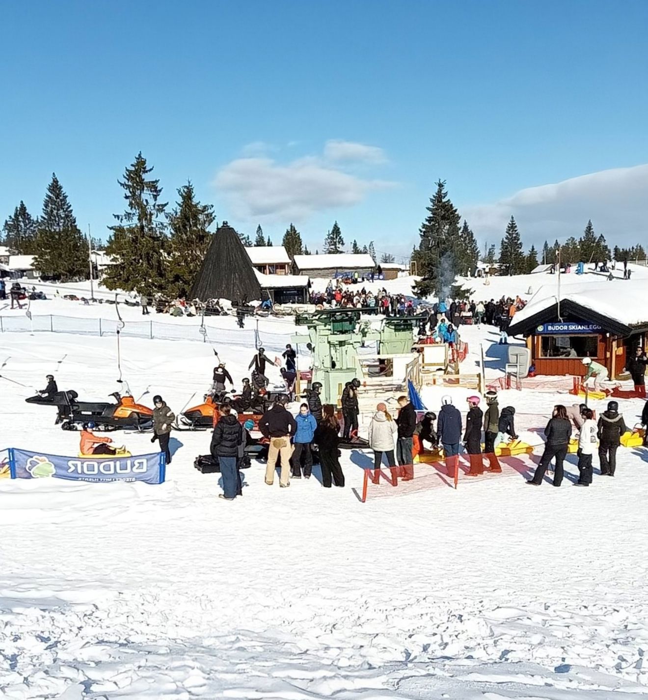 En gruppe mennesker som står på en snødekt ås En gruppe mennesker som står på en snødekt ås