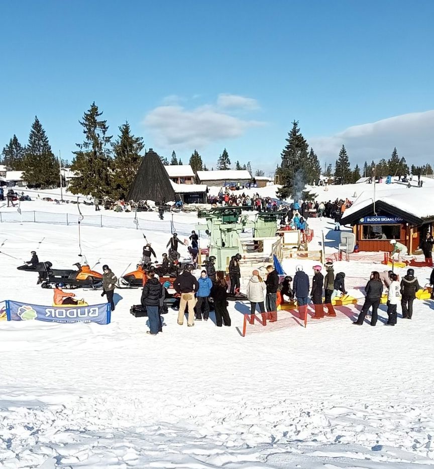 En gruppe mennesker som står på en snødekt ås En gruppe mennesker som står på en snødekt ås